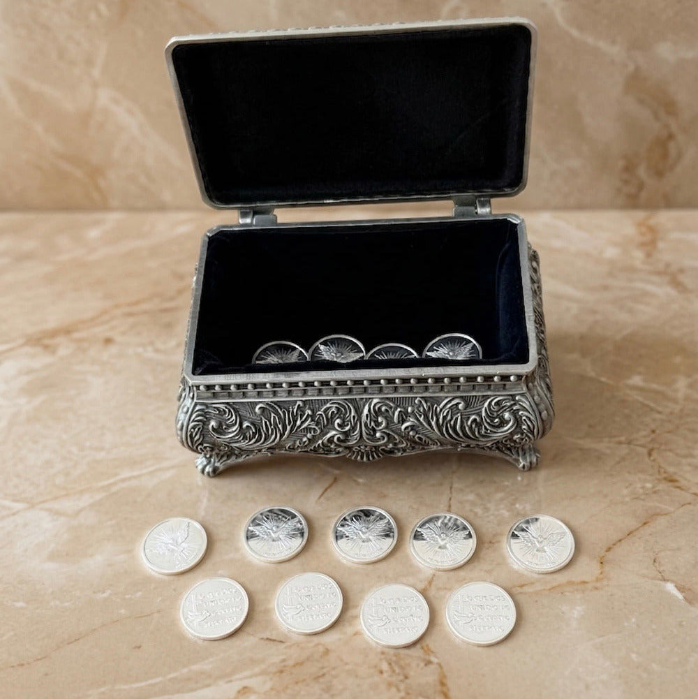Trece arras matrimoniales plateadas con diseño del Espíritu Santo y cofre metálico vintage.