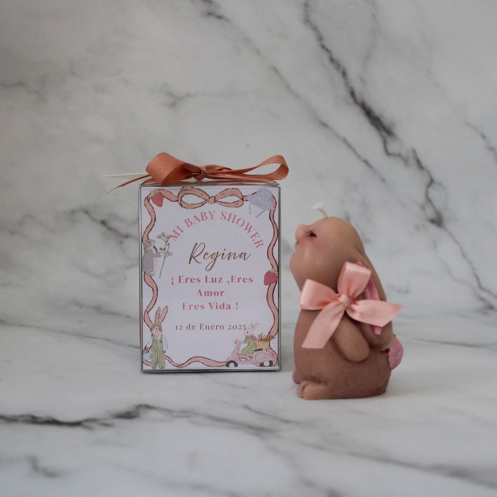 Vela artesanal en forma de conejo para baby shower o bautizo, presentada en caja decorada con listón y etiqueta personalizada.