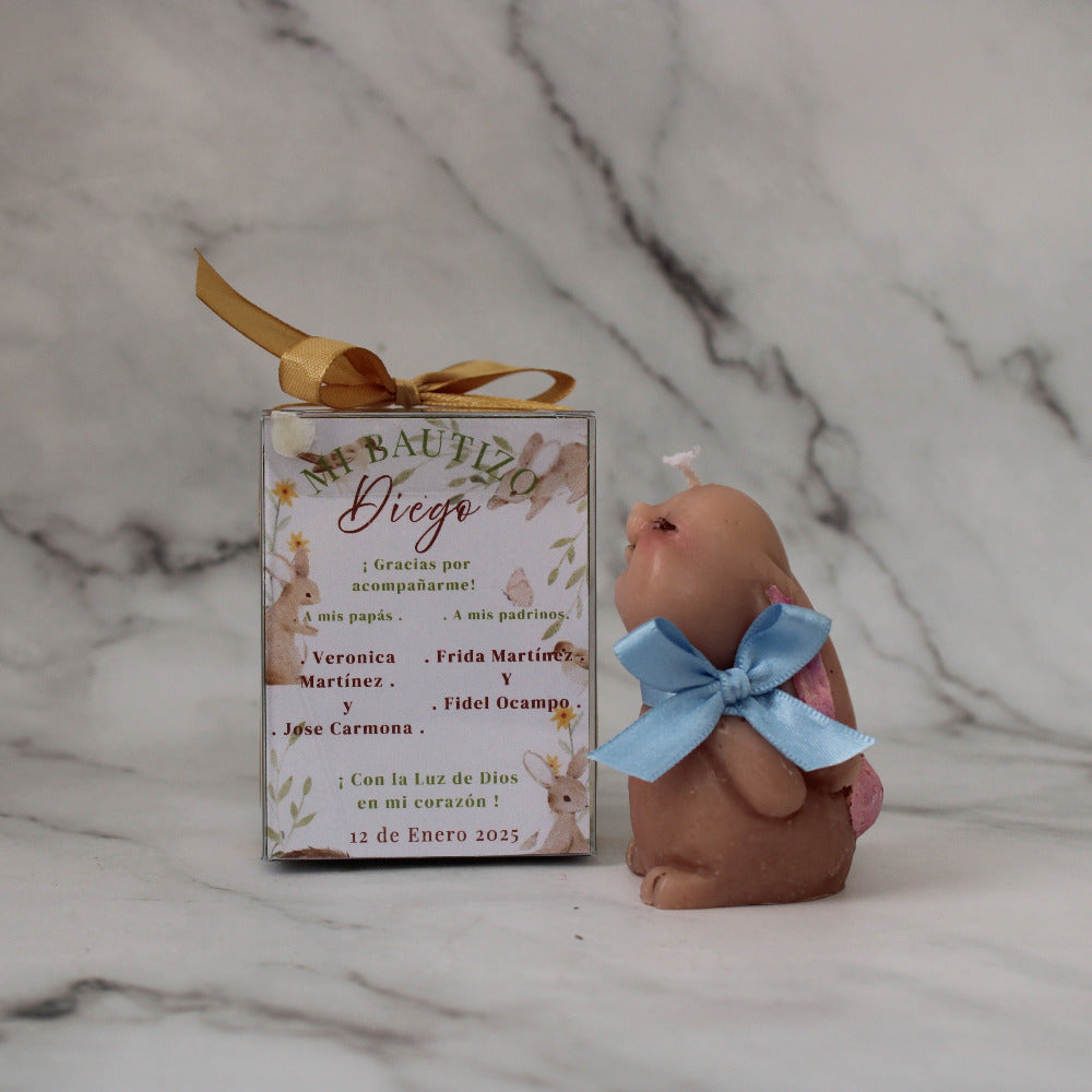 Vela artesanal en forma de conejo para baby shower o bautizo, presentada en caja decorada con listón y etiqueta personalizada.