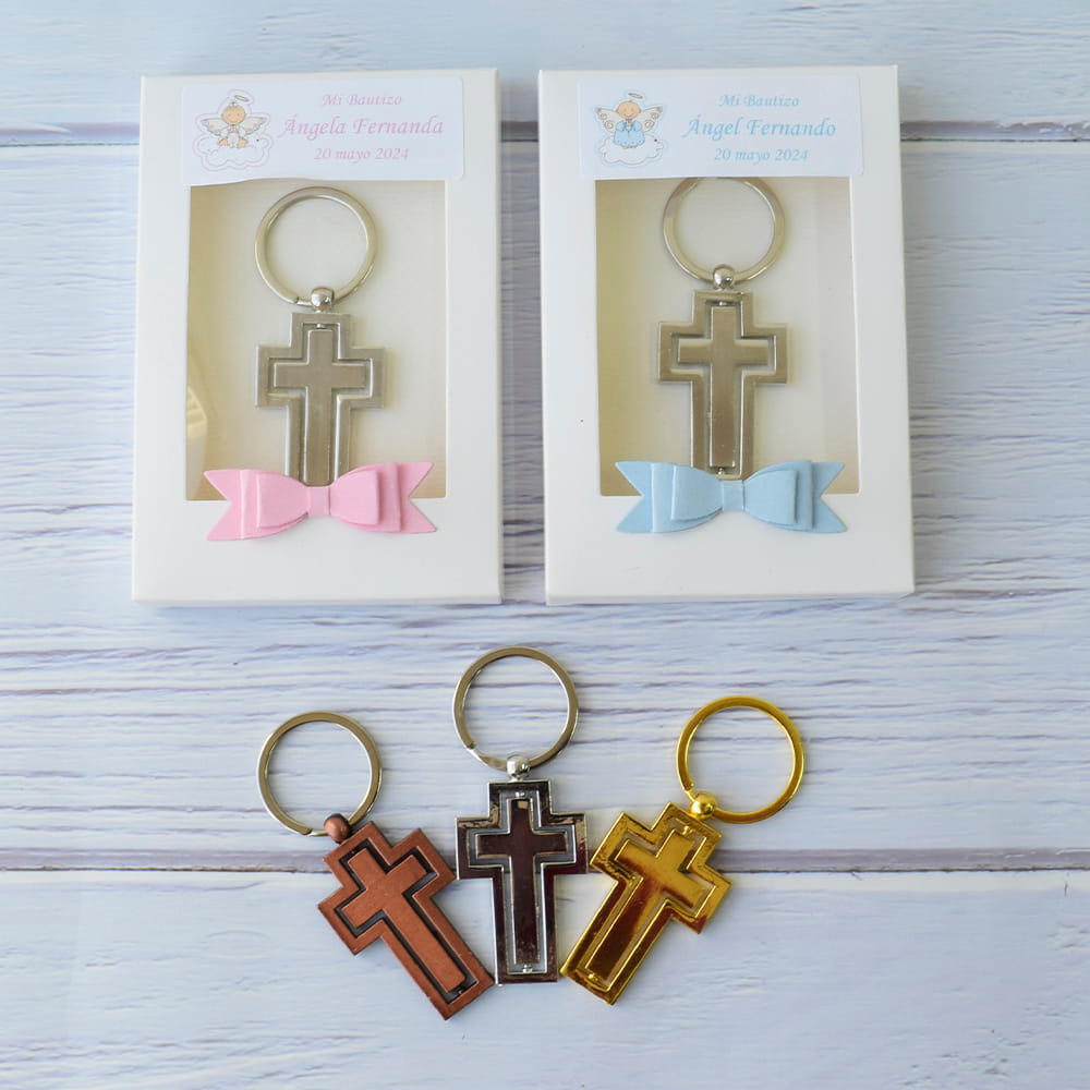 Opciones de llaveros de cruz para recuerdos de bautizo, disponibles en acabados metálicos de bronce, plata y oro, mostrados con cajas de presentación.