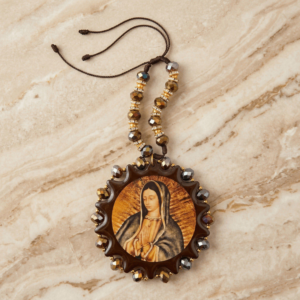 Recuerdo religioso colgante con imagen de la Virgen María en tonos cafés y dorados, decorado con cuentas facetadas y pedrería.