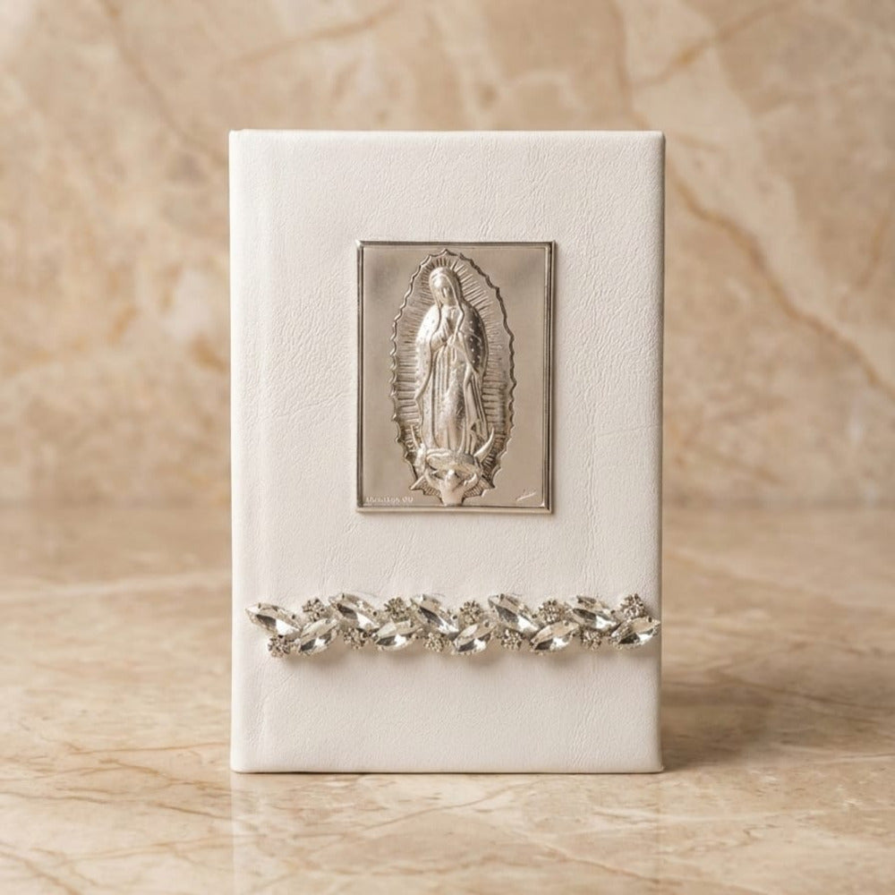 Biblia de boda con forro blanco, placa de plata laminada de la Virgen de Guadalupe y detalle inferior de pedrería fina.