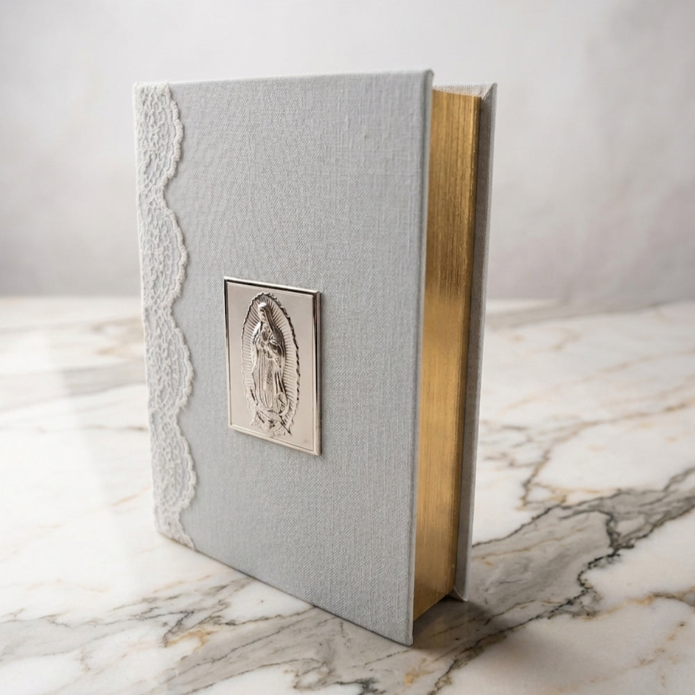 Biblia de boda con forro de lino gris, encaje lateral, placa de plata de la Virgen y cantos dorados.