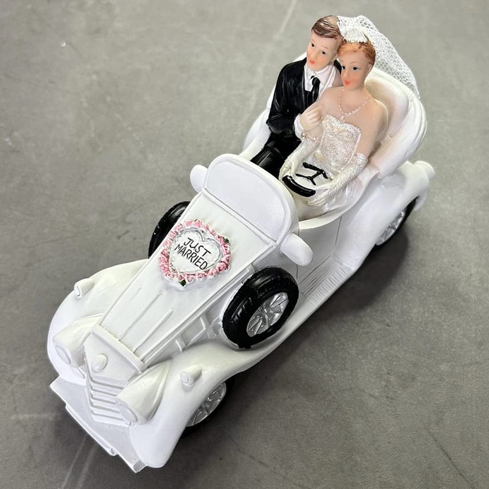 Figura para pastel de boda de novios en un coche clásico blanco con letrero 'Just Married' decorado con flores.