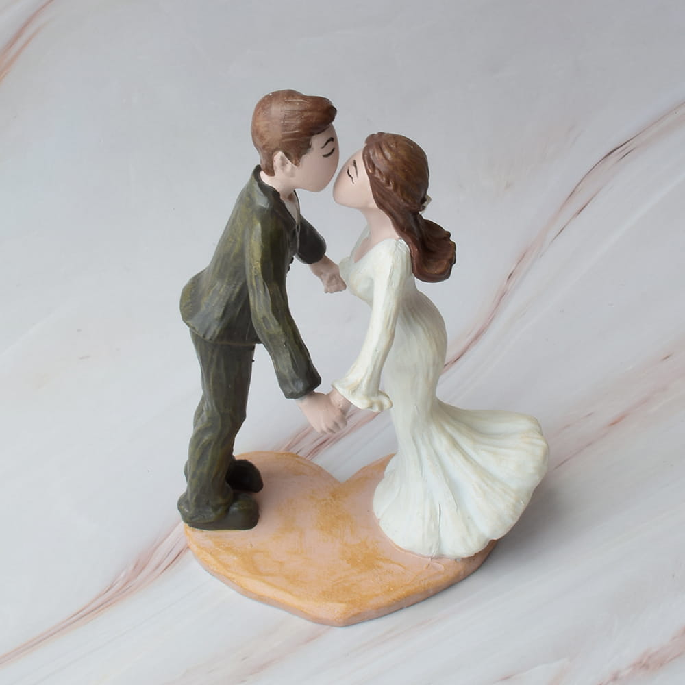 Figura decorativa de pareja de novios besándose sobre base en forma de corazón, muñeco de boda con traje verde y vestido blanco, adorno romántico para pastel o recuerdo de matrimonio.