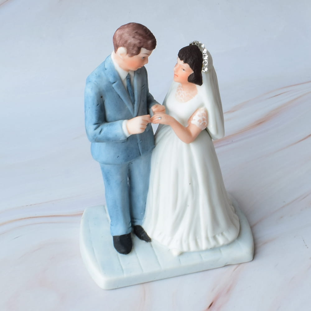 Figura de novios para pastel de boda: pareja de recién casados en porcelana, novio en traje azul y novia con velo y vestido blanco clásico, detalle romántico vintage