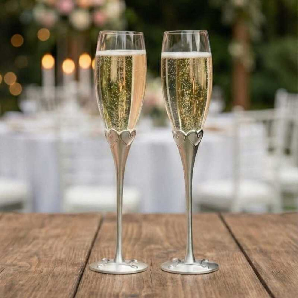 Set de dos copas para brindis de novios con tallos metálicos esbeltos y detalle de corazones en la base del cáliz, elegantes flautas de cristal para celebraciones de boda y aniversario.