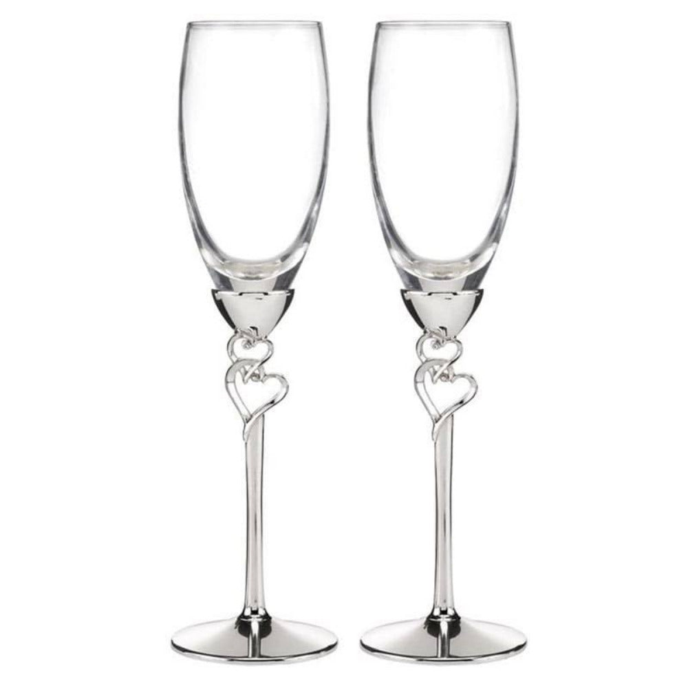 Set de dos flautas de champán de cristal con tallos metálicos plateados y diseño de corazones entrelazados, ideales para el brindis de los novios y decoración de mesas de boda.