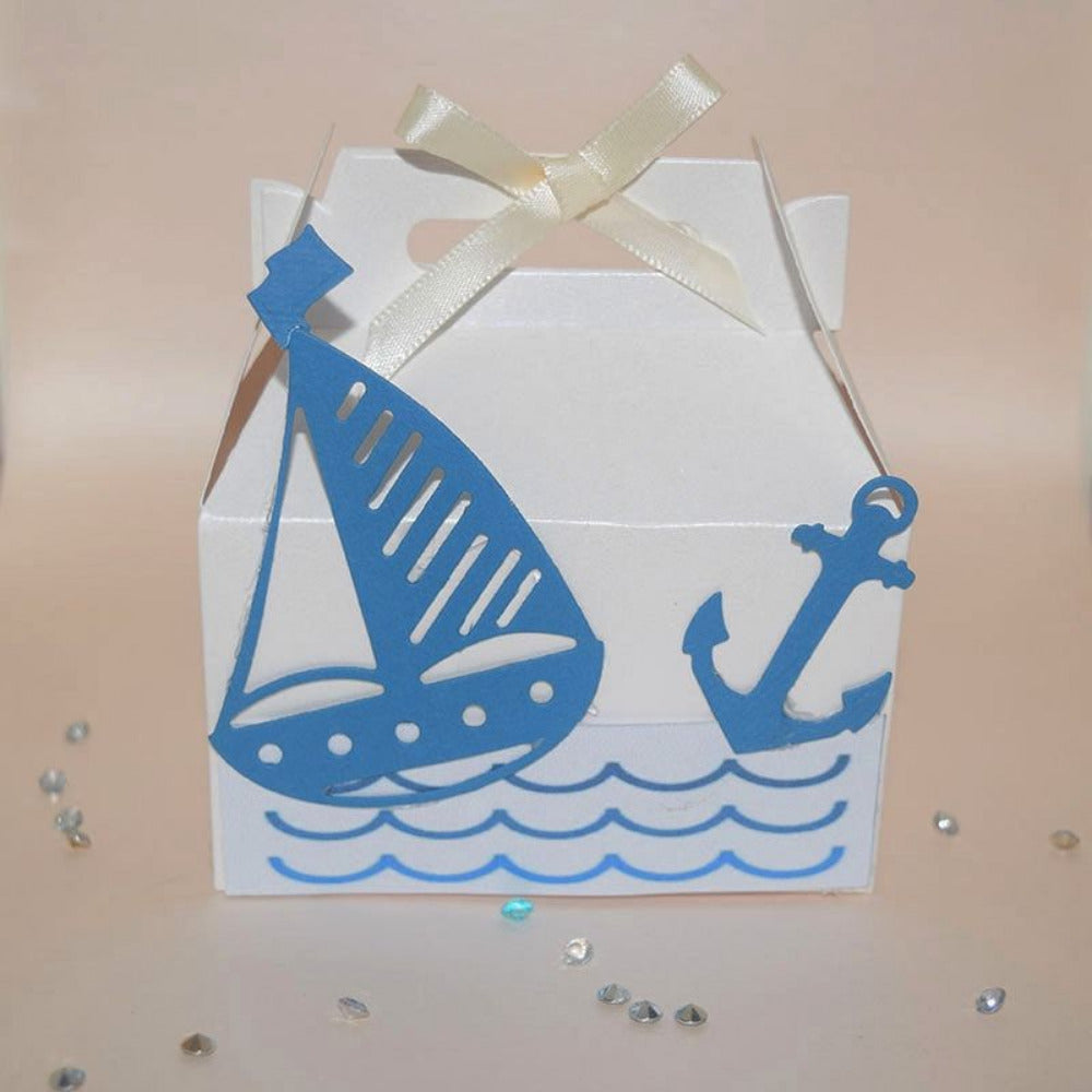 Cajita dulcero para bautizo o baby shower con temática de marinero, diseño de velero y ancla en corte láser azul sobre blanco con moño satinado.