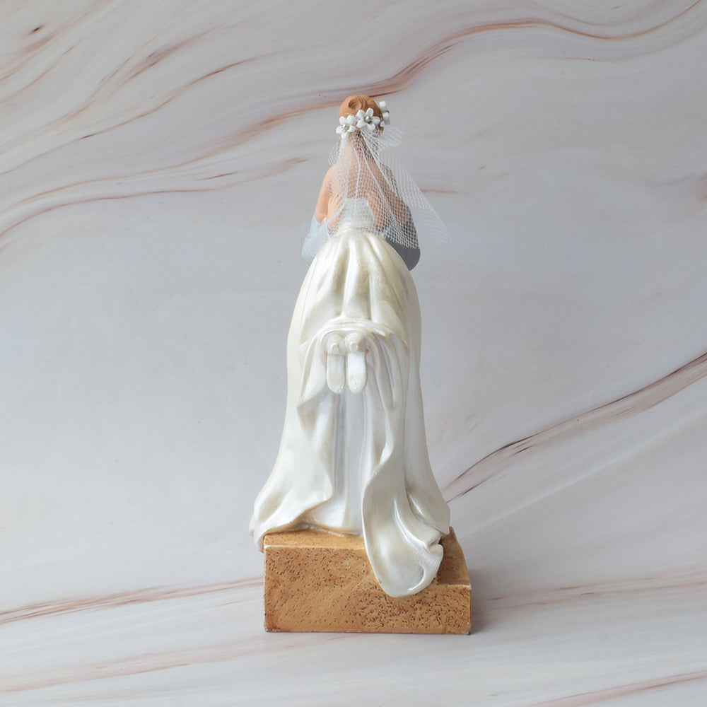 Figura para pastel de boda con novio cargando a la novia, diseño romántico y detallado sobre fondo de mármol.