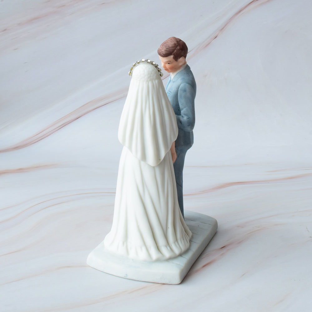 Figura para pastel de bodas con pareja de novios en actitud romántica sobre fondo de mármol.