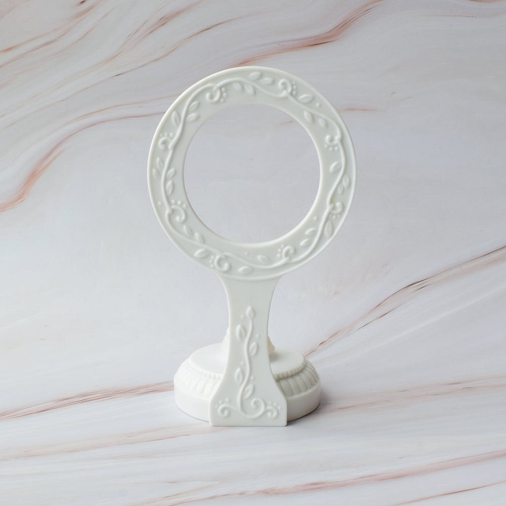 Base para figura de pastel en cerámica blanca con diseño circular y detalles de hojas en relieve sobre mármol.