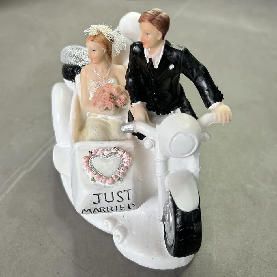 Figura para pastel de bodas con pareja de novios en motocicleta sobre fondo blanco.
