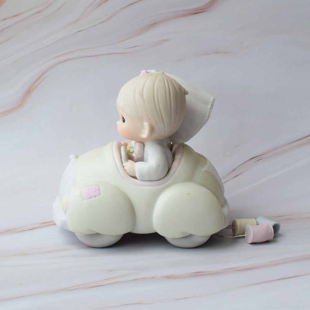 Figura para pastel Precious Moments con novios abrazados, estilo porcelana en tonos suaves, ideal para decoración de bodas elegantes.