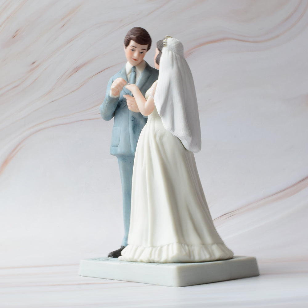 Figura para pastel de bodas con pareja de novios en actitud romántica sobre fondo de mármol.