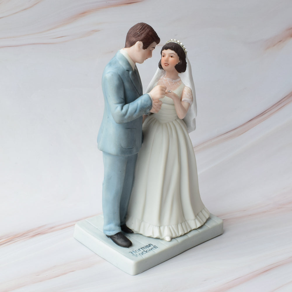 Figura para pastel de bodas con pareja de novios en actitud romántica sobre fondo de mármol.