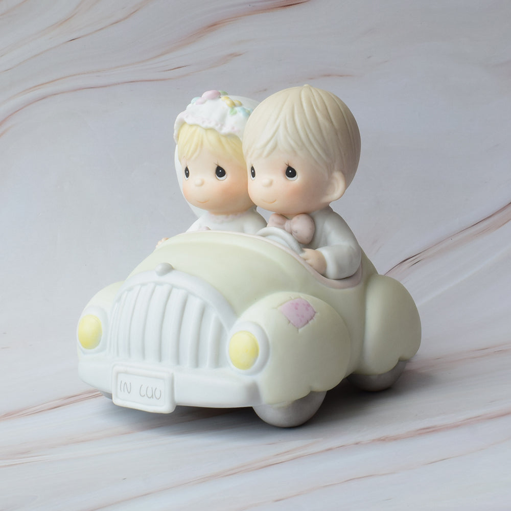 Figura para pastel Precious Moments con novios abrazados, estilo porcelana en tonos suaves, ideal para decoración de bodas elegantes.