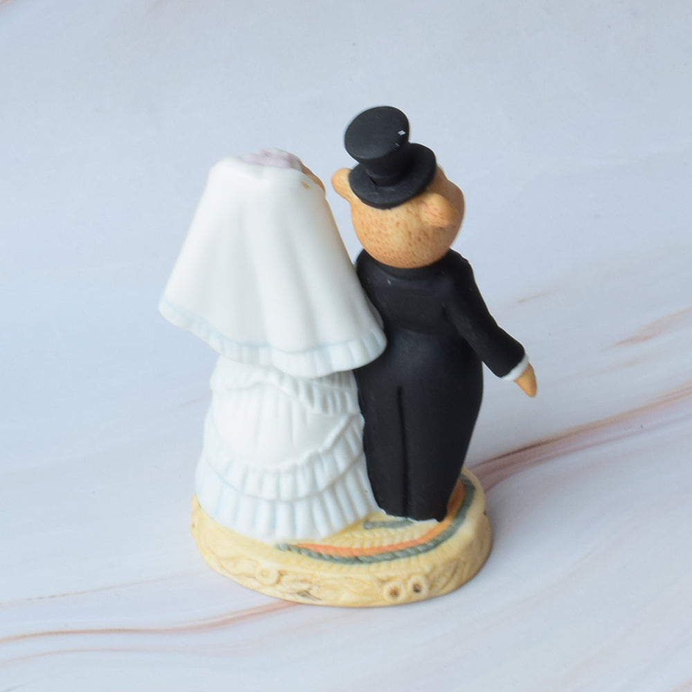 Figura para pastel de boda con pareja de ositos estilo caricatura, abrazados y con detalles florales, sobre fondo blanco.