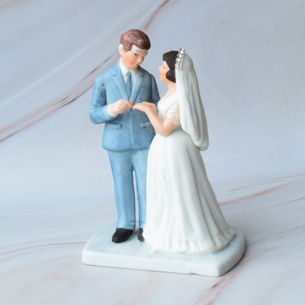 Figura para pastel de bodas con pareja de novios en actitud romántica sobre fondo de mármol.