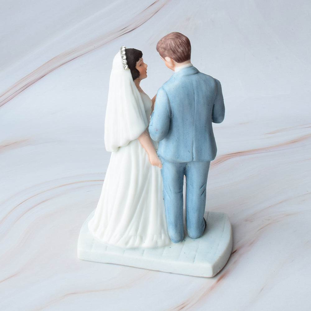 Figura para pastel de bodas con pareja de novios en actitud romántica sobre fondo de mármol.