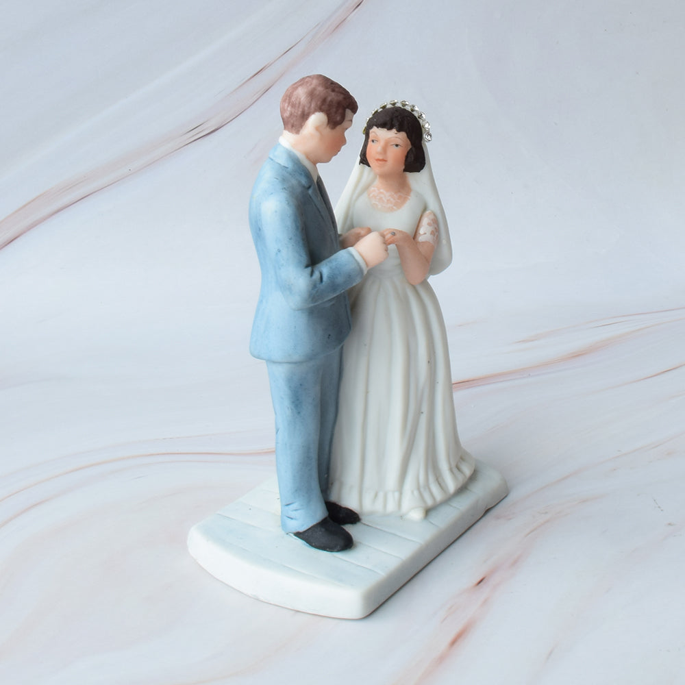 Figura para pastel de bodas con pareja de novios en actitud romántica sobre fondo de mármol.