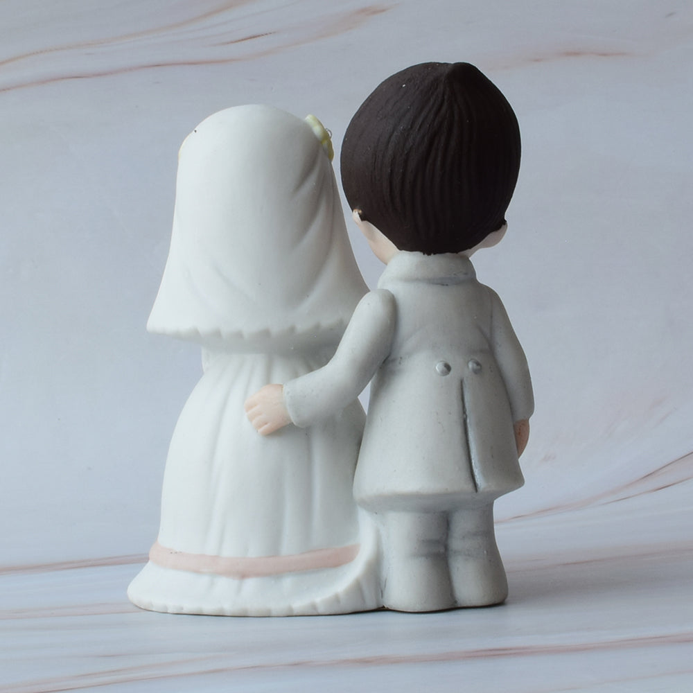 Figura para pastel de bodas con pareja de novios de espaldas sobre fondo de mármol.