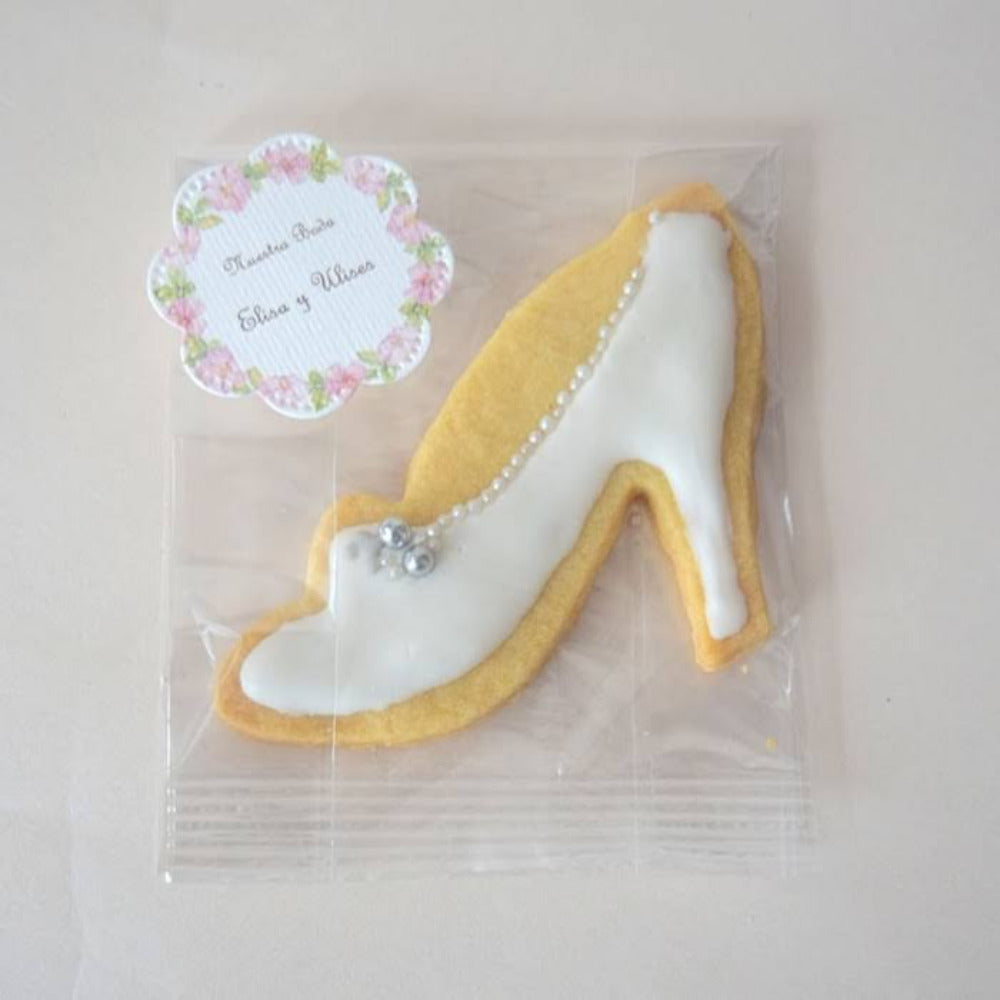 Galleta artesanal decorada en forma de zapatilla de novia con glaseado blanco y detalles de perlas, ideal como recuerdo personalizado para bodas y mesas de dulces.