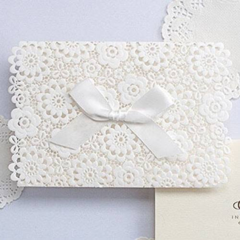 Invitación de boda elegante con diseño de encaje floral en corte láser blanco y moño de listón satinado, papelería personalizada para eventos.