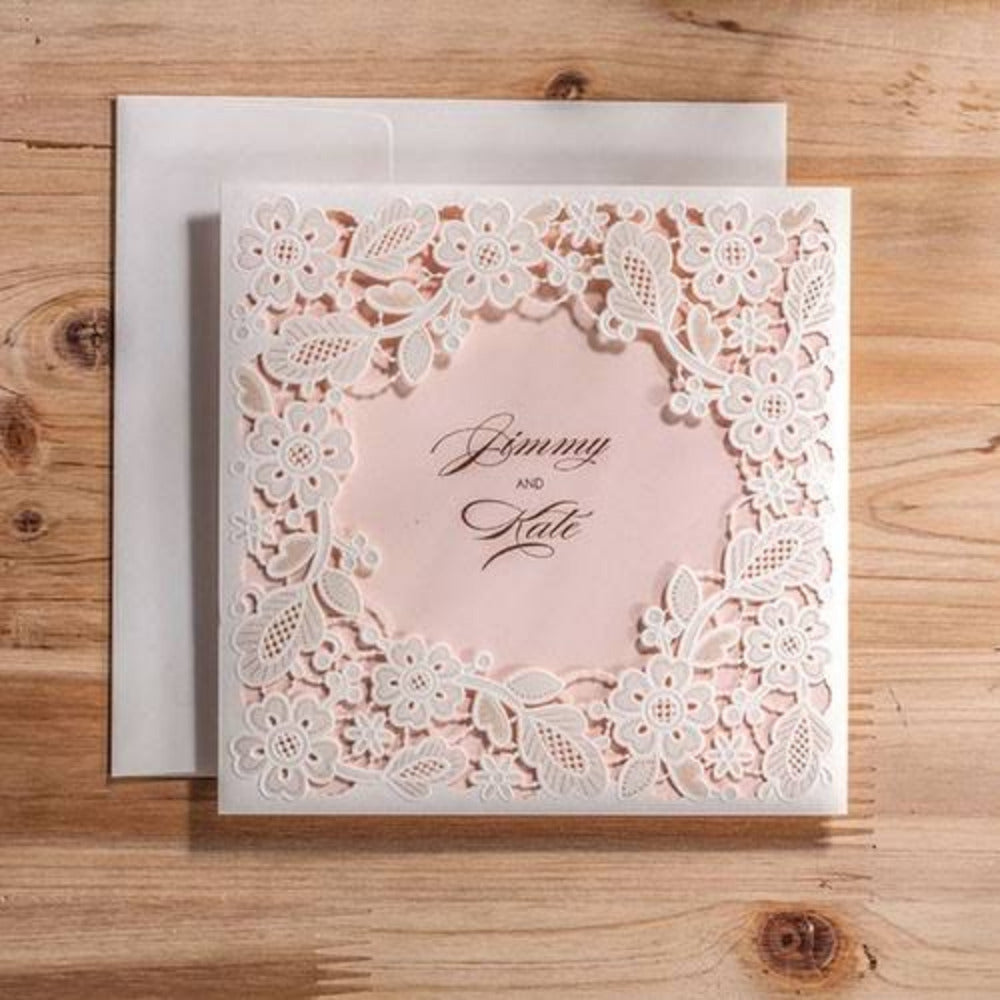Invitación de boda con diseño de corte láser floral en color blanco sobre fondo rosa pastel, papelería elegante y personalizada para nupcias.