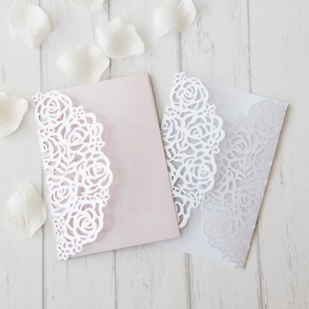 Invitaciones de boda y XV años con sobre de corte láser floral en color blanco, disponibles en fondo rosa pastel y blanco, papelería elegante y personalizada.