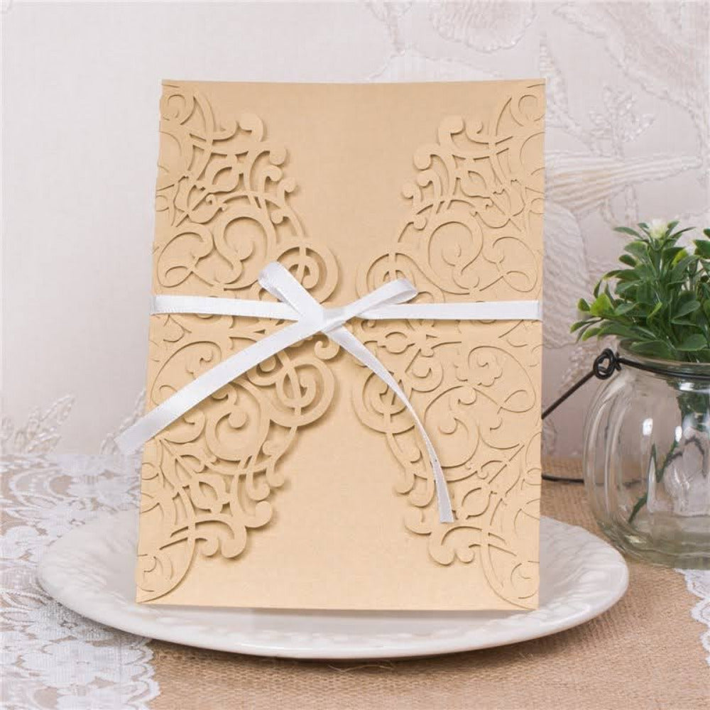 Invitación de boda con sobre de corte láser en cartulina color beige y moño de listón satinado blanco, papelería elegante y sencilla.
