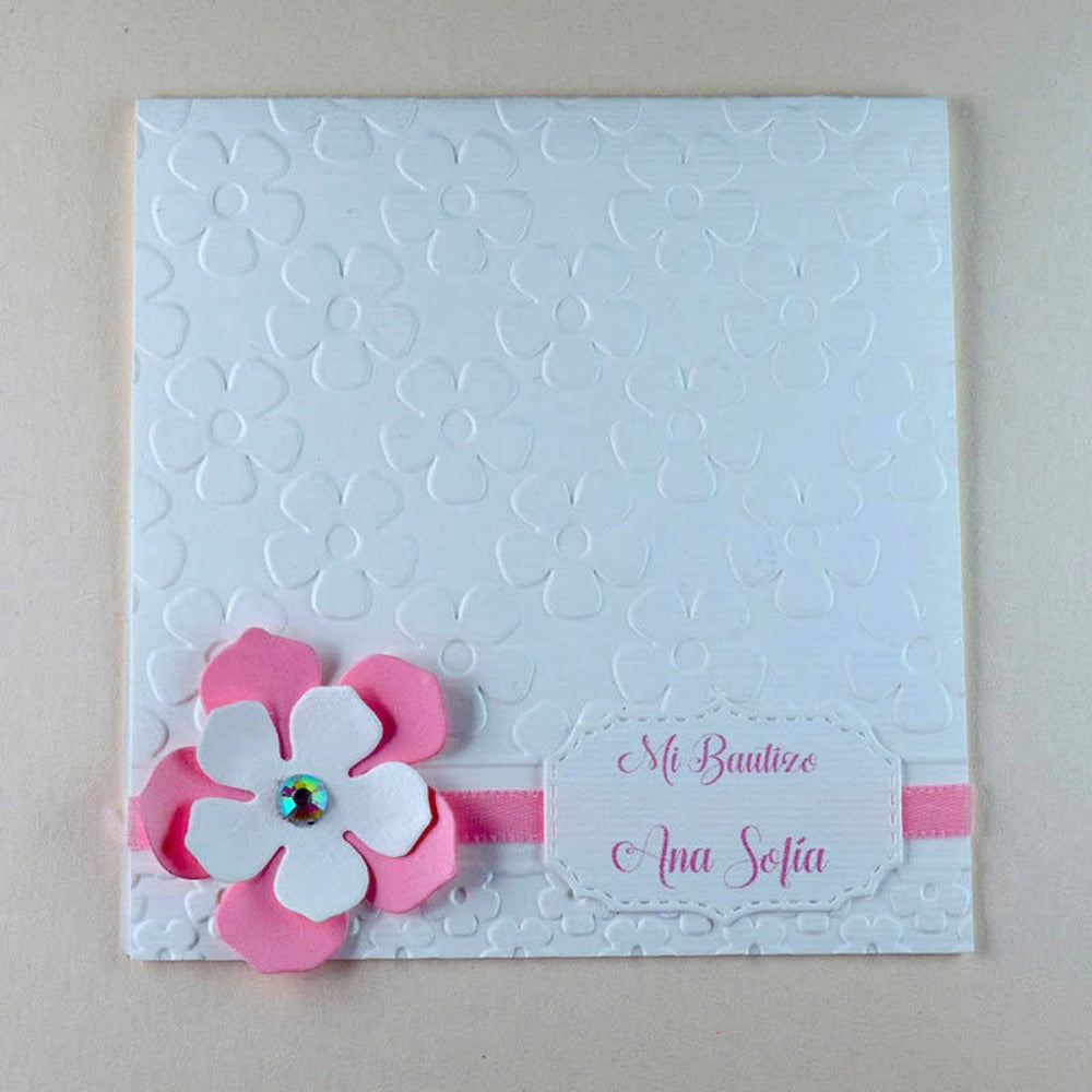 Invitación de bautizo para niña hecha a mano con textura de flores en relieve, detalle de flor de papel en 3D rosa y etiqueta personalizada.