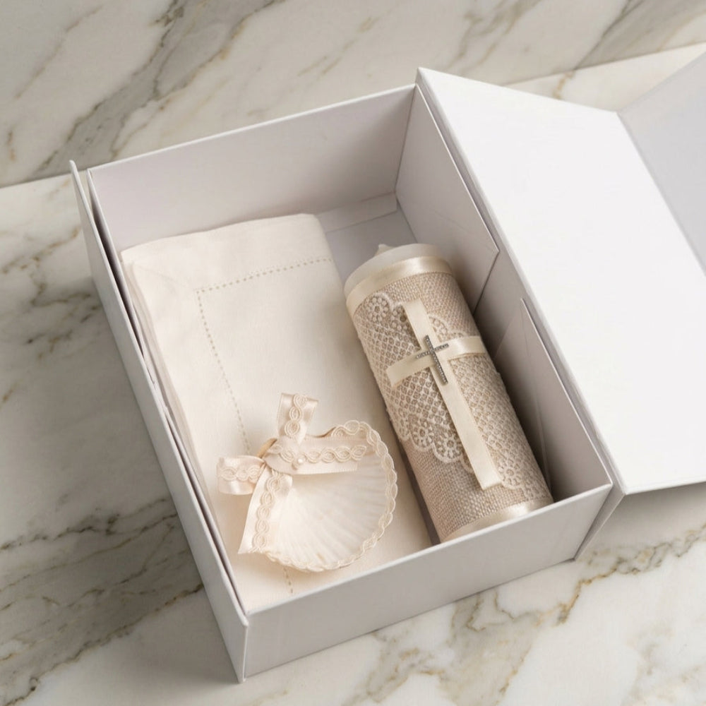 Kit de bautizo artesanal en caja blanca con cirio de encaje, cruz de cristales, concha natural y paño bordado.