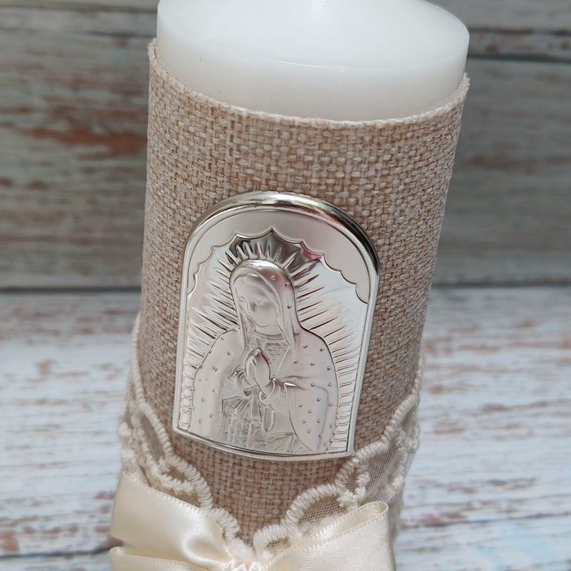Cirio para bautizo forrado en tela beige con placa de plata laminada de la Virgen de Guadalupe sobre mármol.