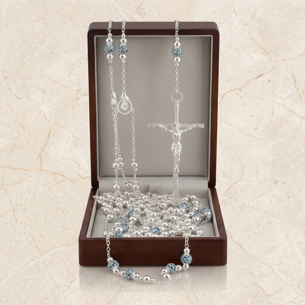 Lazo de boda con cuentas blancas, detalles en azul y cruz plateada, presentado en estuche de madera de nogal.