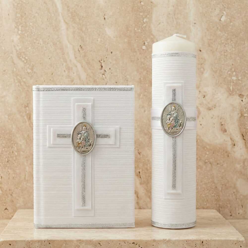 Kit de Primera Comunión compuesto por un libro y un cirio de color blanco con textura acanalada. Ambos artículos están decorados con detalles plateados, una cruz en relieve y un medallón metálico ovalado en el centro con la imagen del Ángel de la Guarda