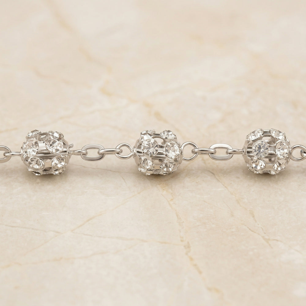 Acercamiento detallado de un lazo de boda con múltiples cuentas de cristal brillantes y enlaces.