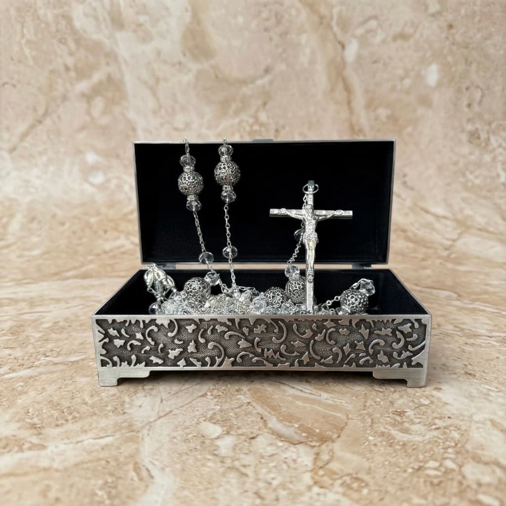 Lazo de boda de plata con cruz italiana en cofre plateado ornamentado sobre mármol para ceremonias religiosas y nupciales.