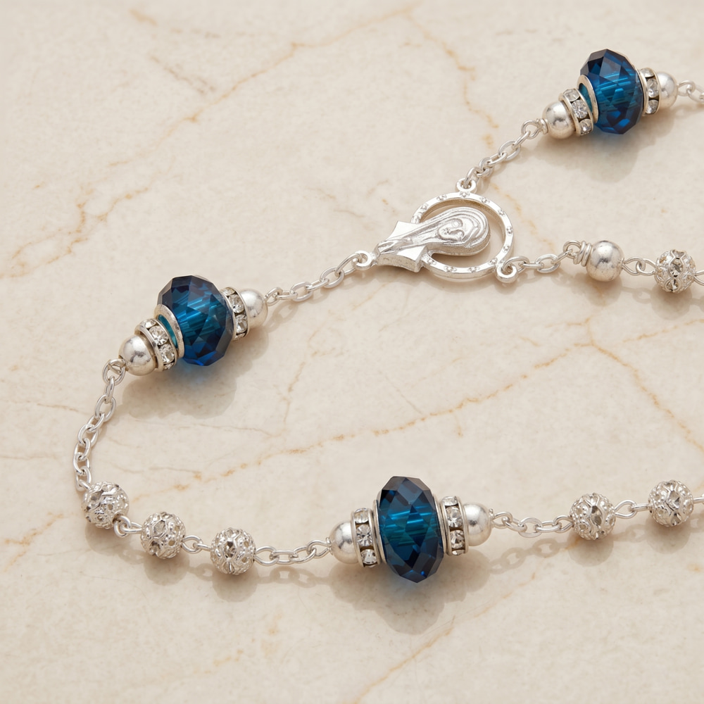 Lazo de boda plateado con cuentas de cristal azul y una medalla de la Virgen sobre superficie de madera.