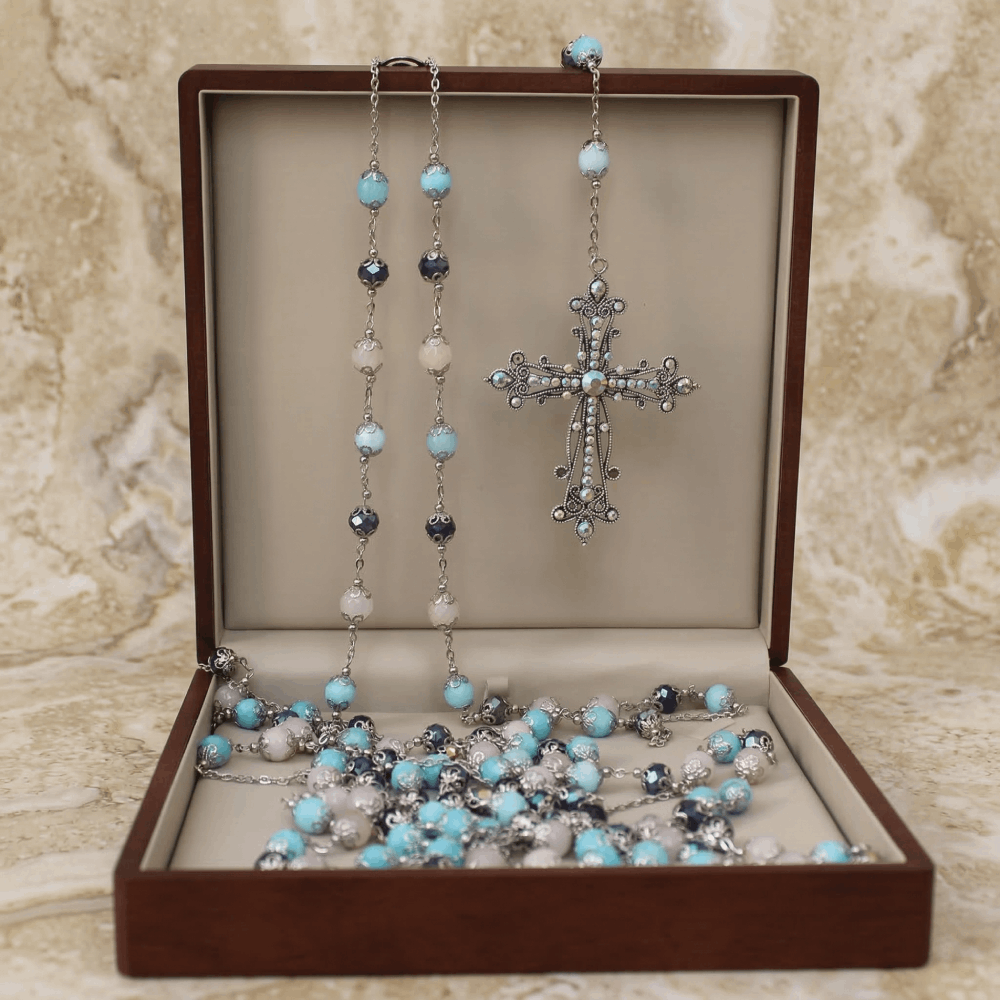 Lazo matrimonial con cuentas de colores y crucifijo de plata, en cofre de nogal abierto.