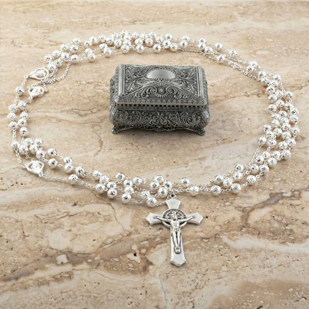 Lazo para boda con baño de plata con un cofre de pewter ornamentada sobre mármol.