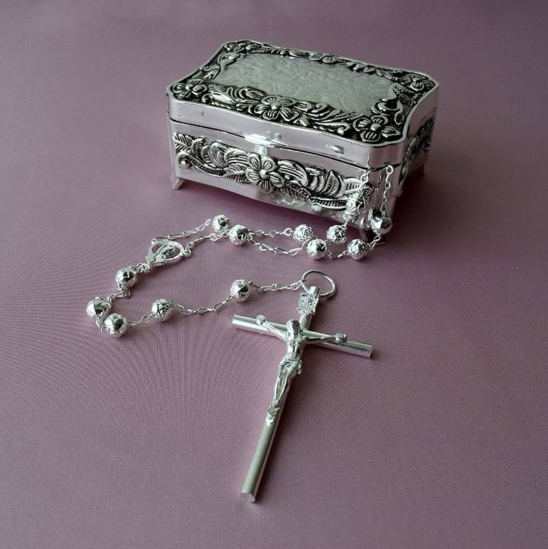 Lazo nupcial de plata con crucifijo detallado y estuche metálico grabado, accesorio elegante para ceremonias religiosas de boda.
