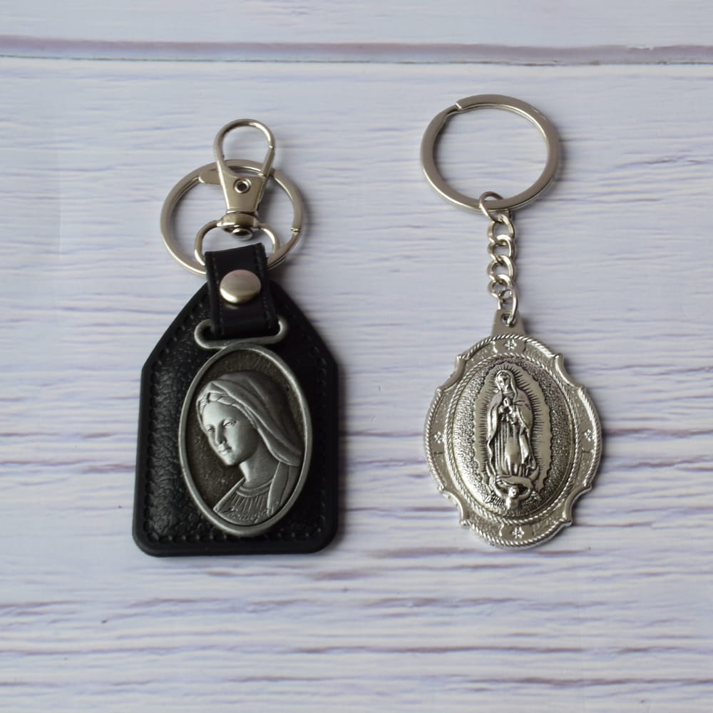 Dos llaveros religiosos para recuerdo luctuoso: uno de cuero negro con el perfil en metal de la Virgen María y otro completamente de metal con la imagen de la Virgen de Guadalupe.