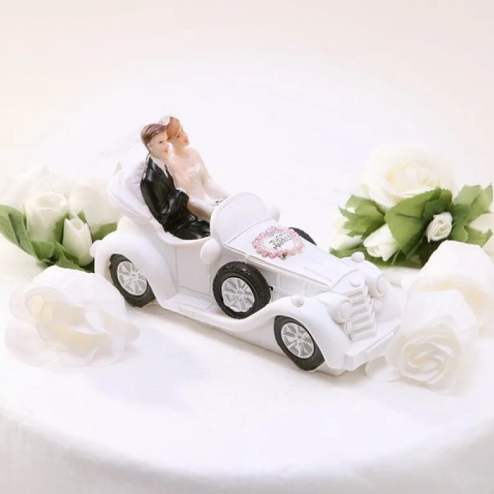 Figura para pastel de bodas con novios en coche clásico blanco y letrero "Just Married" sobre fondo blanco.