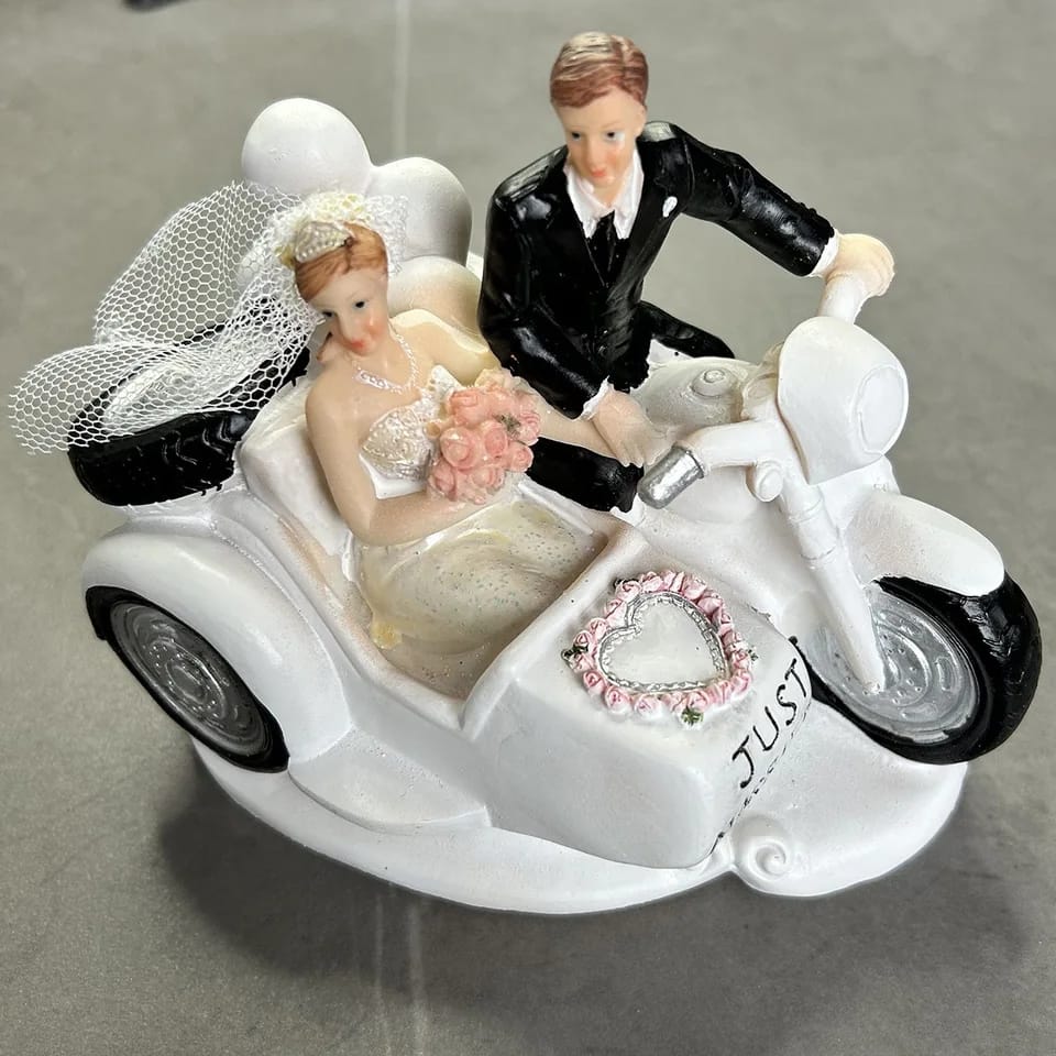 Figura para pastel de bodas con pareja de novios en motocicleta sobre fondo blanco.
