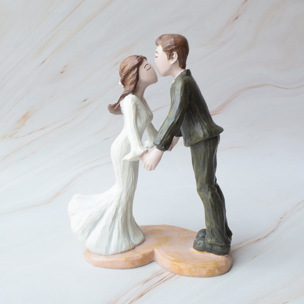 Figuras para pastel de boda con novios dándose un dulce beso, diseño romántico y moderno sobre fondo de mármol.