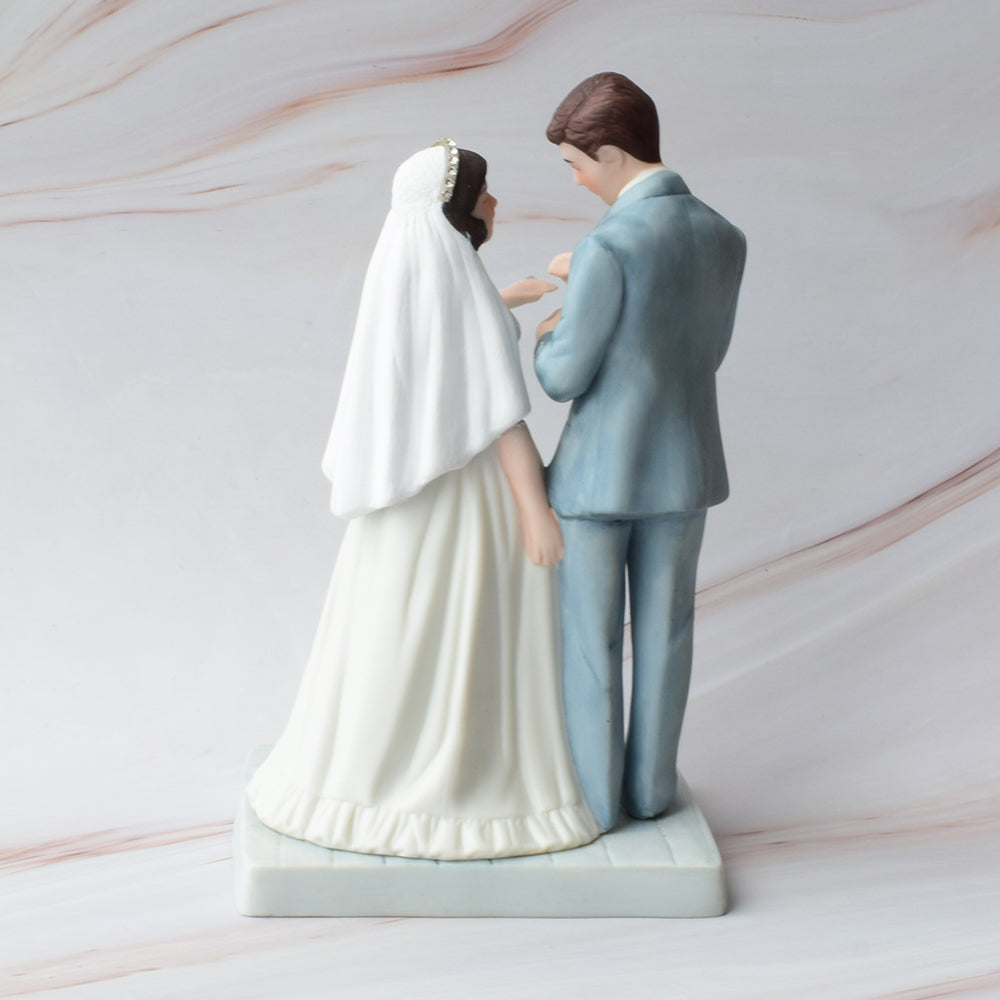 Figura para pastel de bodas con pareja de novios en actitud romántica sobre fondo de mármol.