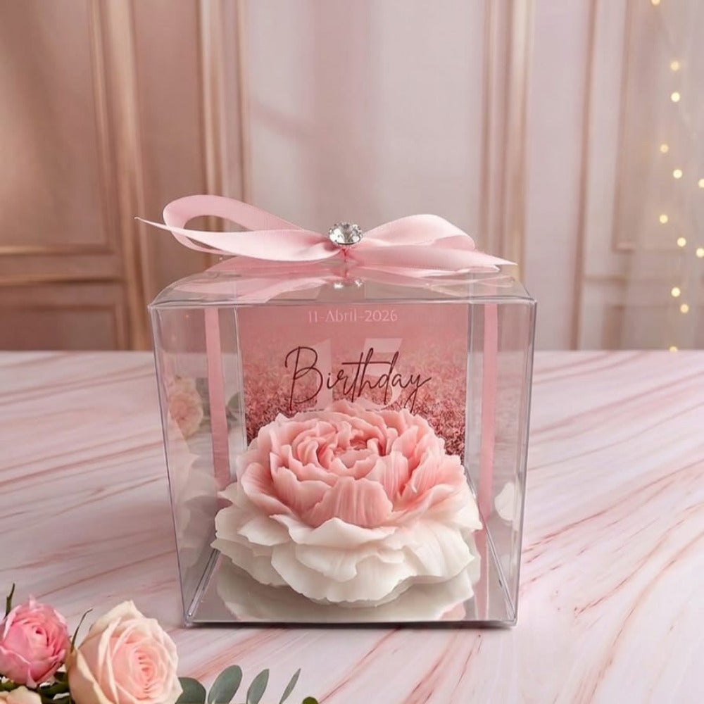 Vela artesanal en forma de peonía rosa y blanca, recuerdo de cumpleaños elegante en caja transparente con moño rosa y tarjeta personalizada.