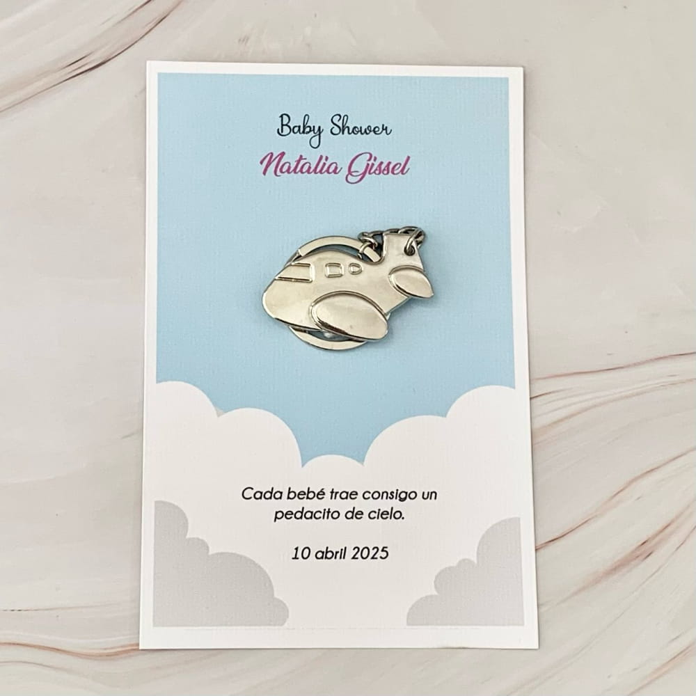 Llavero de avioncito metálico sobre tarjeta personalizable de recuerdo para baby shower con diseño de nubes.