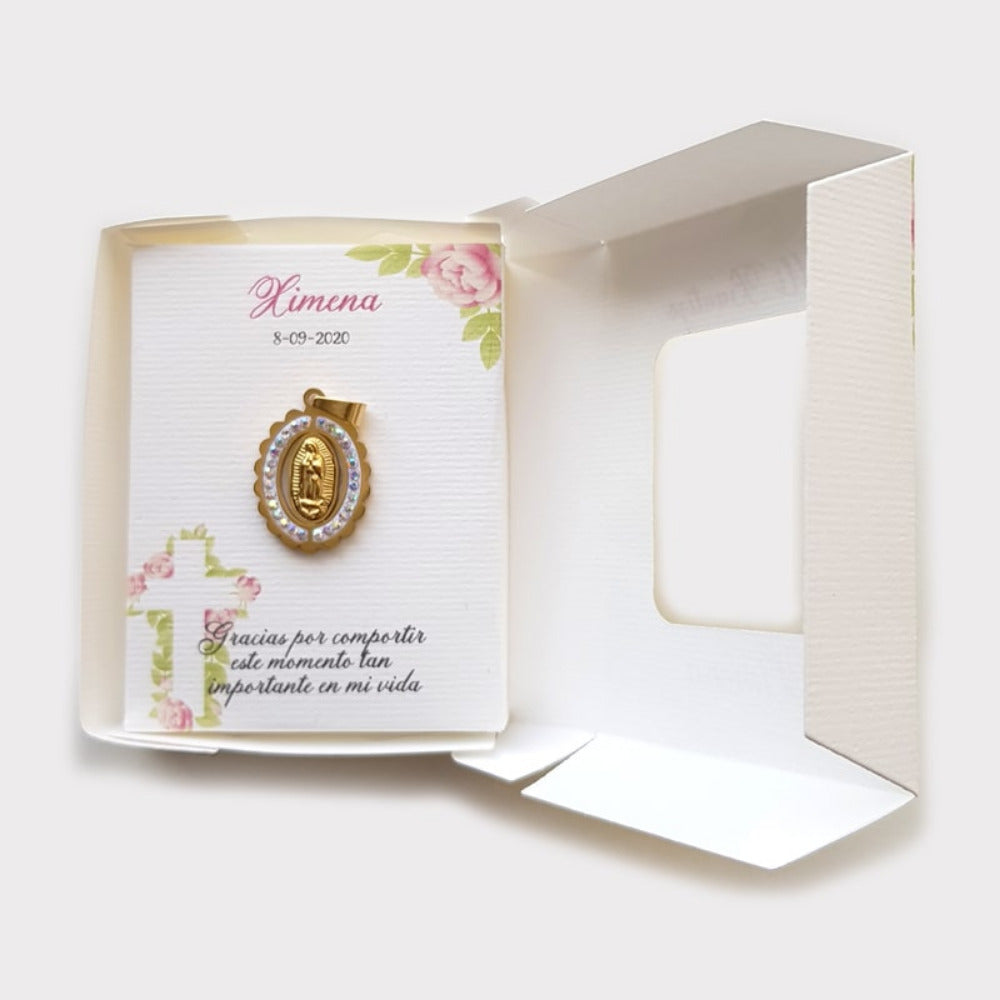 Recuerdo de bautizo para niña con medalla dorada de la Virgen de Guadalupe rodeada de cristales, incluye tarjeta personalizada con diseño floral y caja.